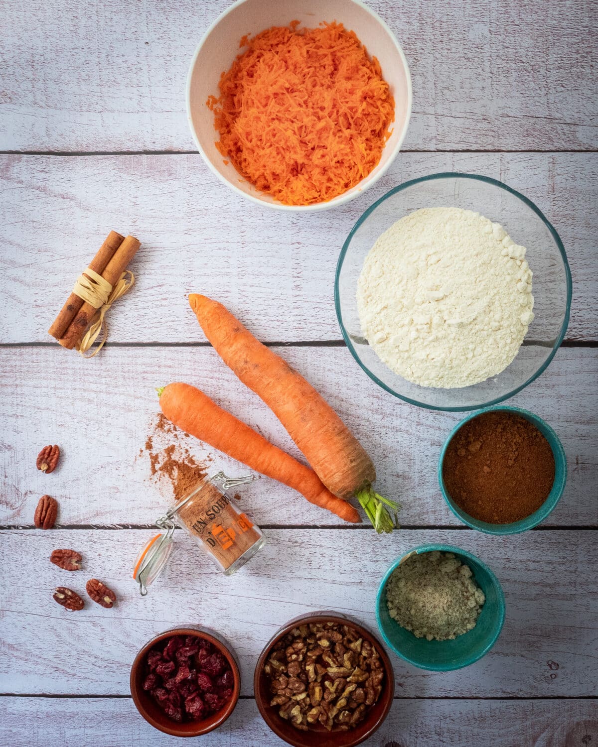 les ingredients pour un carrot cake carottes farine sucre de coco poudre d amande noix cranberries noix de pecan batons de cannelle epices