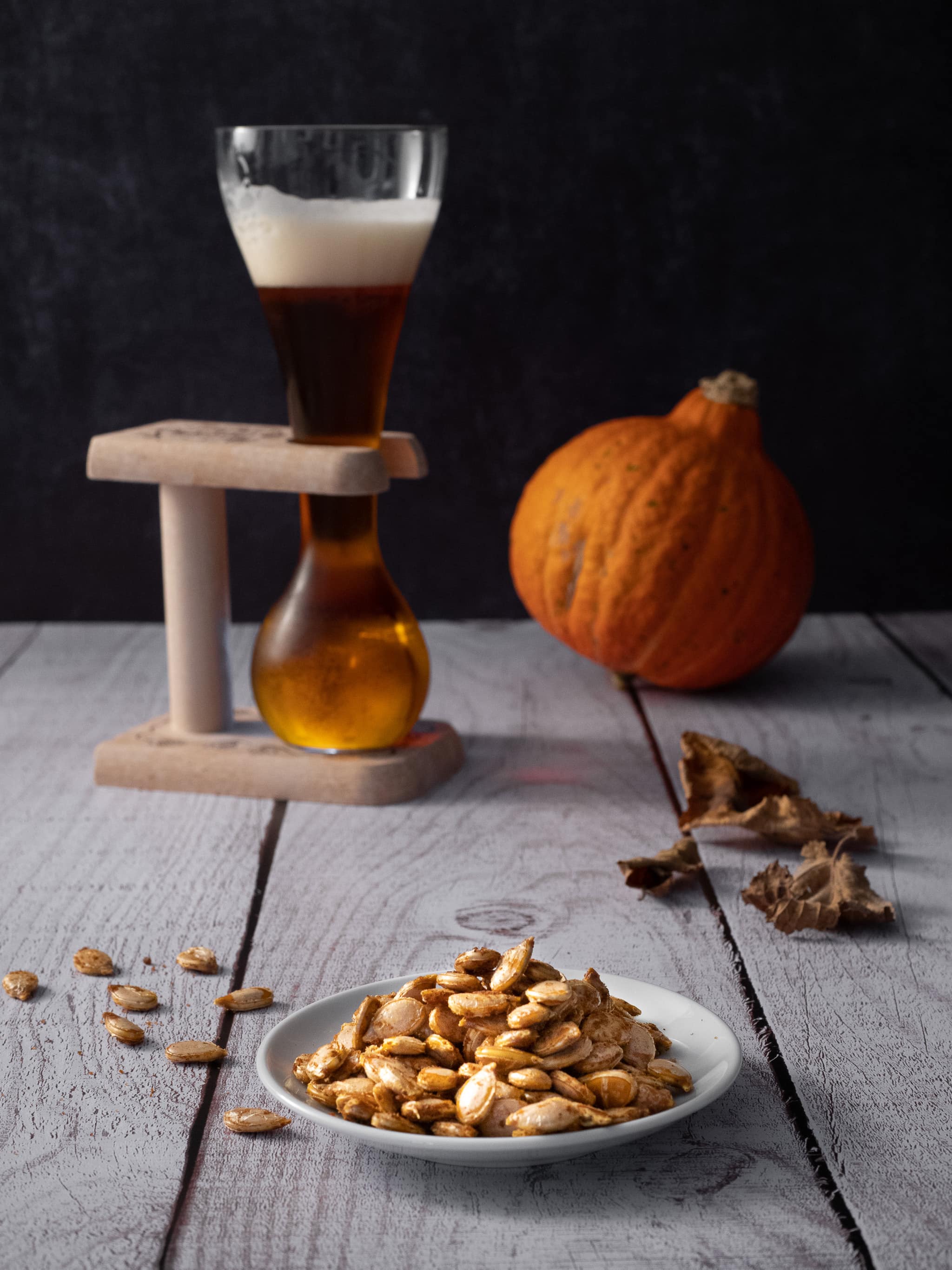 graines de potimarron servies en apéritif avec un verre de bière et un potimarron en arrière plan