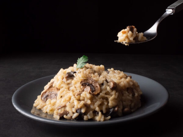 assiette de risotto aux champignons de Paris avec une fourchette au-dessus qui s’apprête à être dégustée