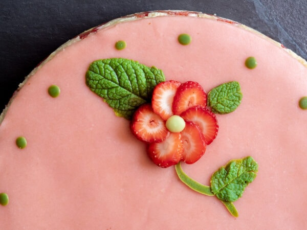 notre fraisier vegan décoré d'une fraise découpée pour former une fleur et de feuilles créées à l'aide d'un chocolat blanc au thé matcha vegan maison