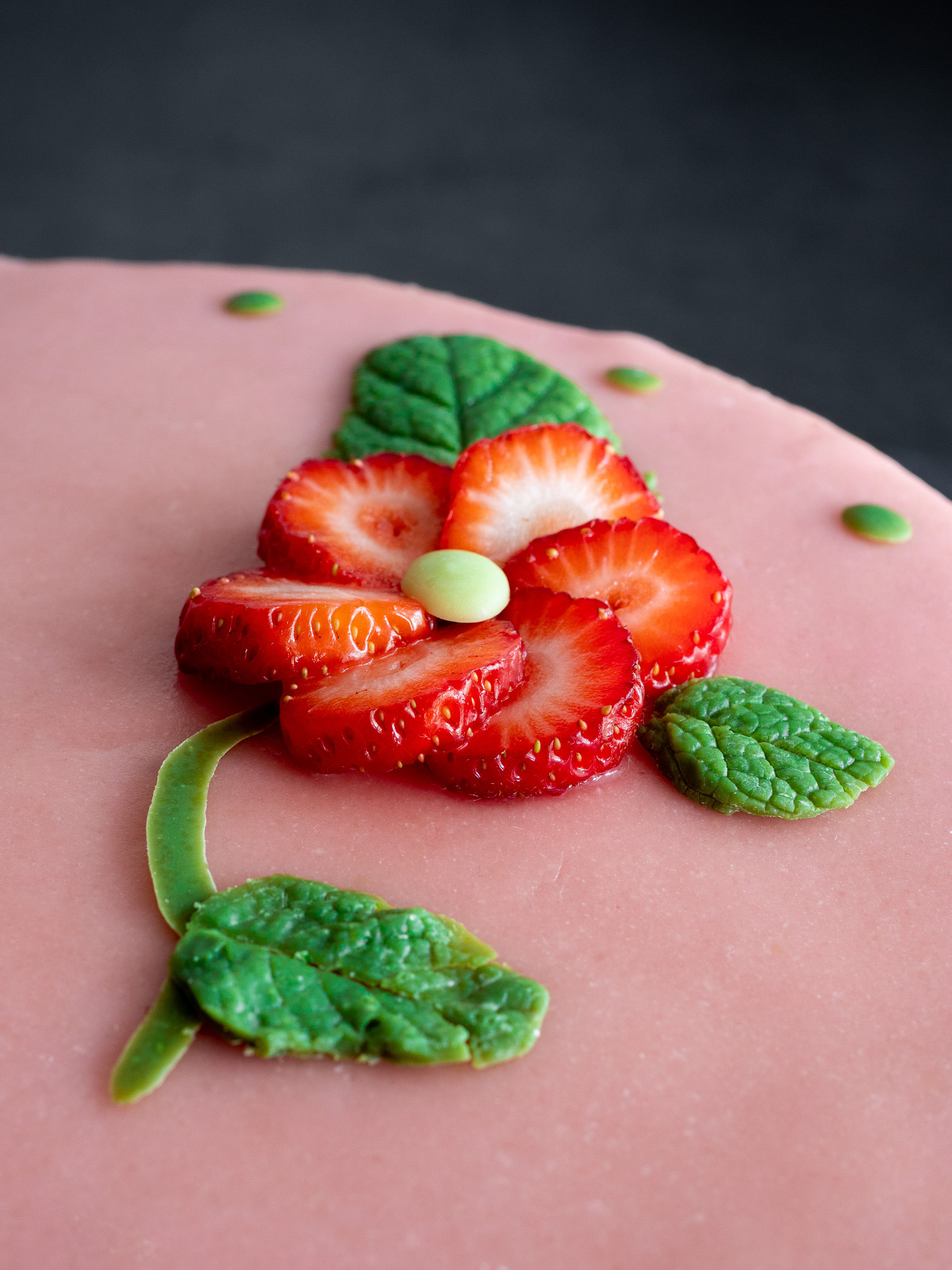 décoration de notre fraisier vegan avec une fleur en rondelle de fraise et des feuilles en chocolat blanc au thé matcha pour le côté vert