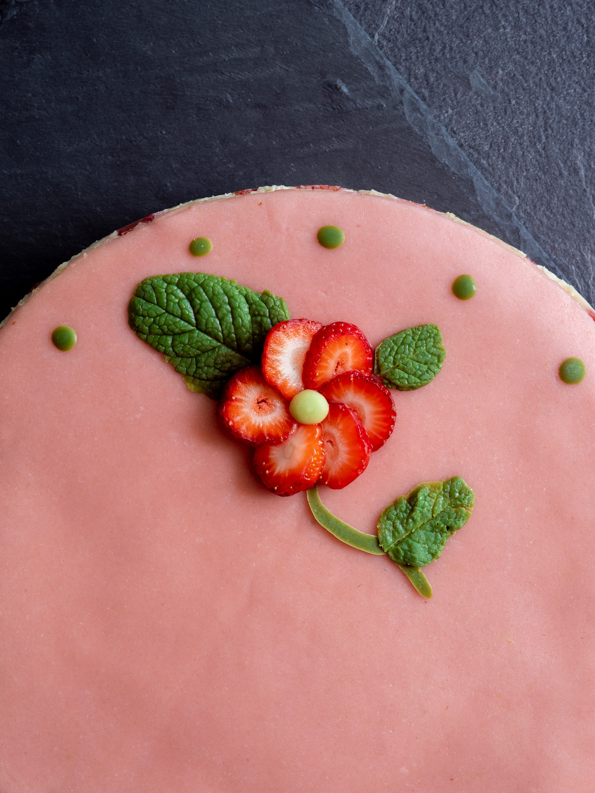 décoration de notre fraisier vegan avec une fleur en rondelle de fraise et des feuilles en chocolat blanc au thé matcha pour le côté vert