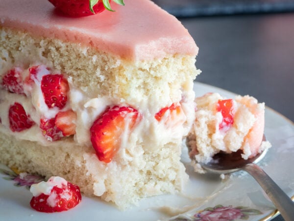 gros plan sur une part de fraisier vegan avec des fraises enrobées de crème mousseline, couchées entre deux génoises moelleuses et aériennes