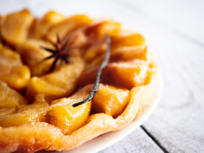 une tarte tatin vegan généreusement garnie en pommes avec une gousse de vanille et une anis étoilée sur le dessus