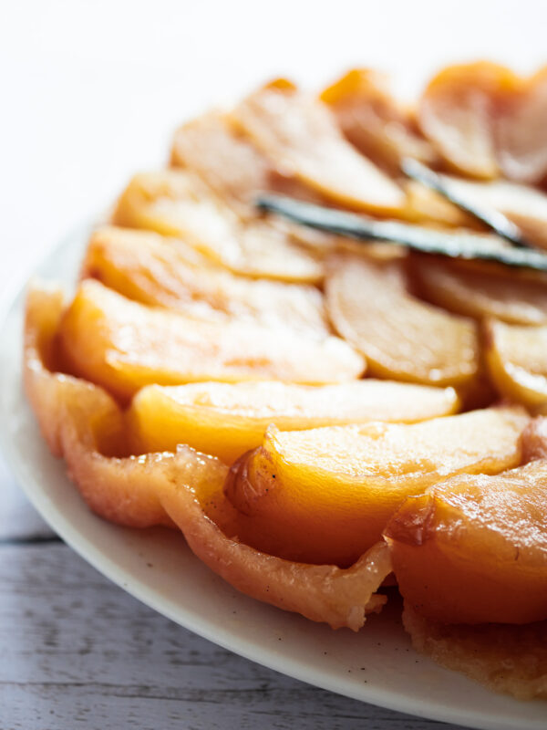 une tarte tatin vegan généreusement garnie en pommes avec deux gousses de vanille sur le dessus