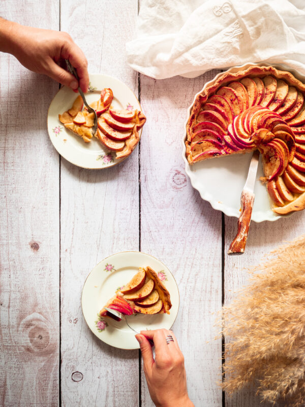 marion et jérémy s'apprêtent à manger une part de tarte aux pommes vegan sur une table en bois