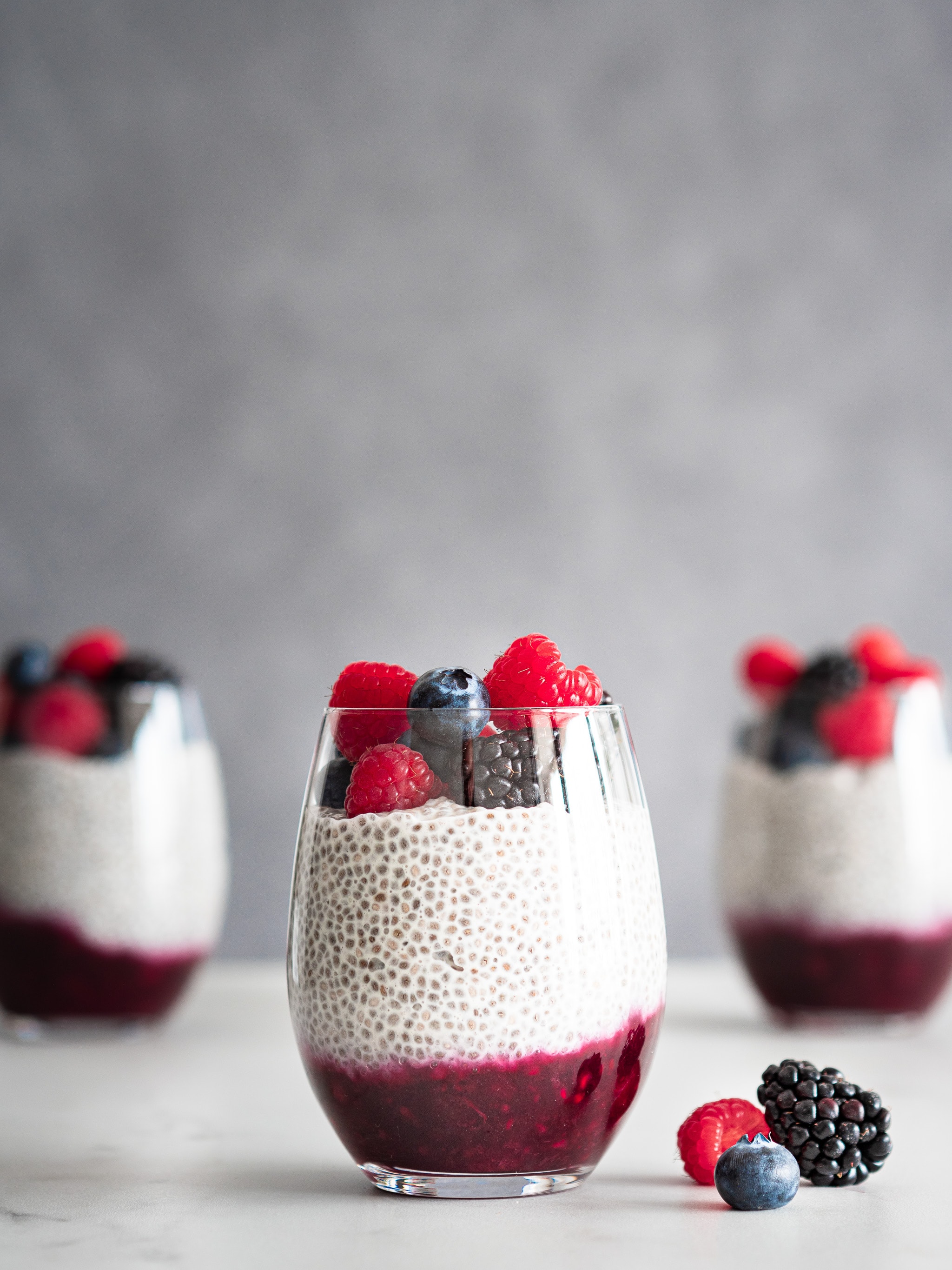 pudding de chia vegan au lait végétal, avec une compotée de fruits rouges en dessous, et des fruits rouges frais sur le dessus